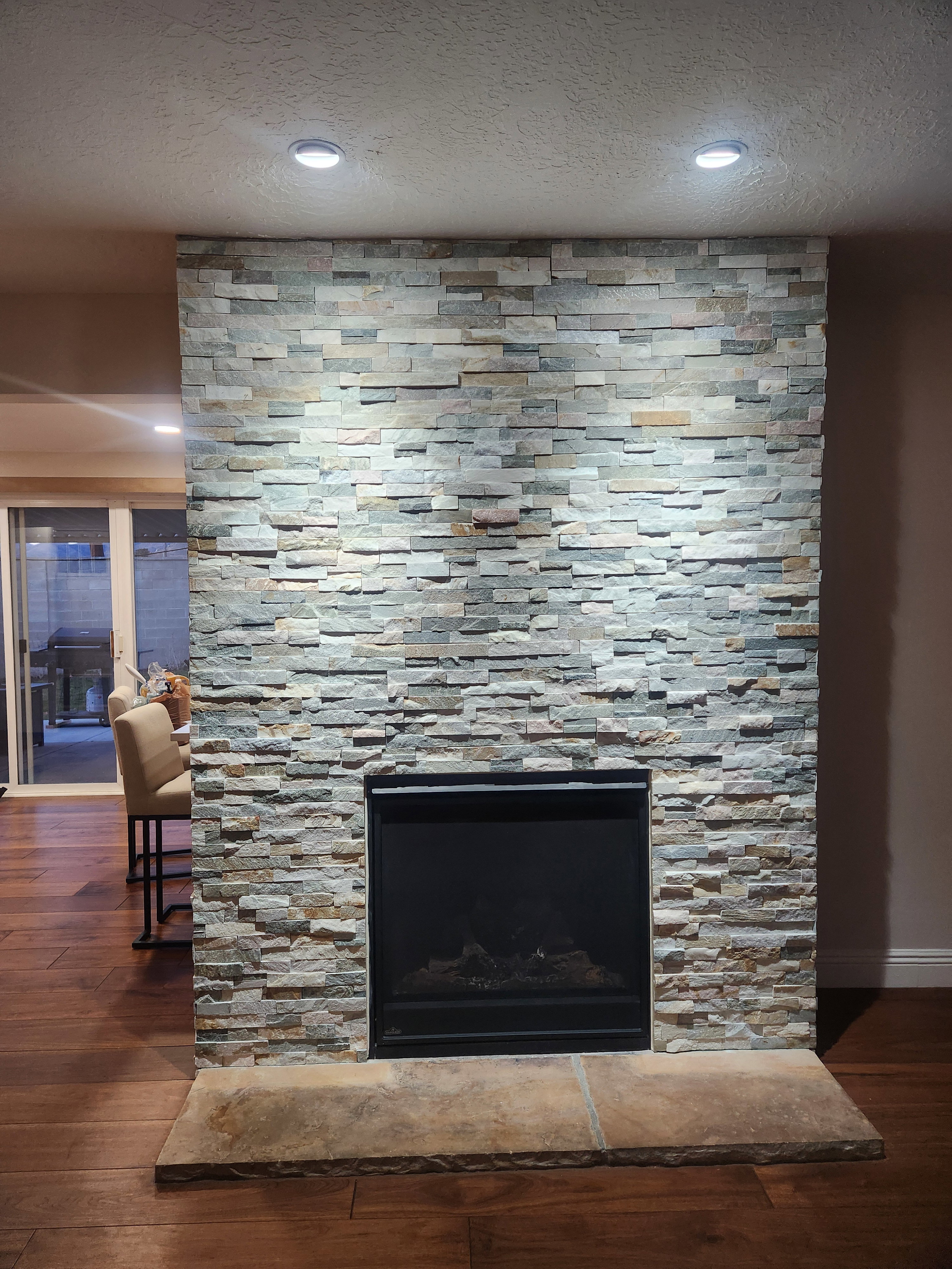 Detailed view of wood finished floors, a textured ceiling, a stone fireplace, and recessed lighting