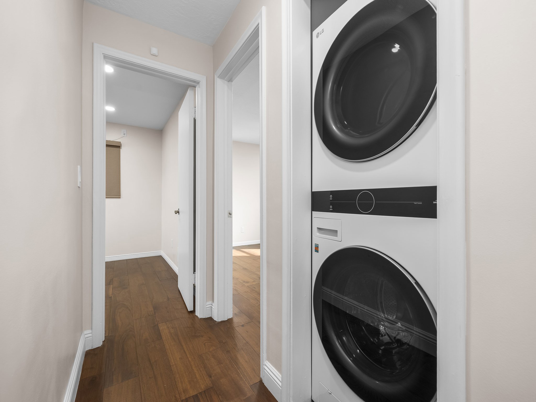 Laundry area featuring dark wood-style flooring and stacked washer and clothes dryer