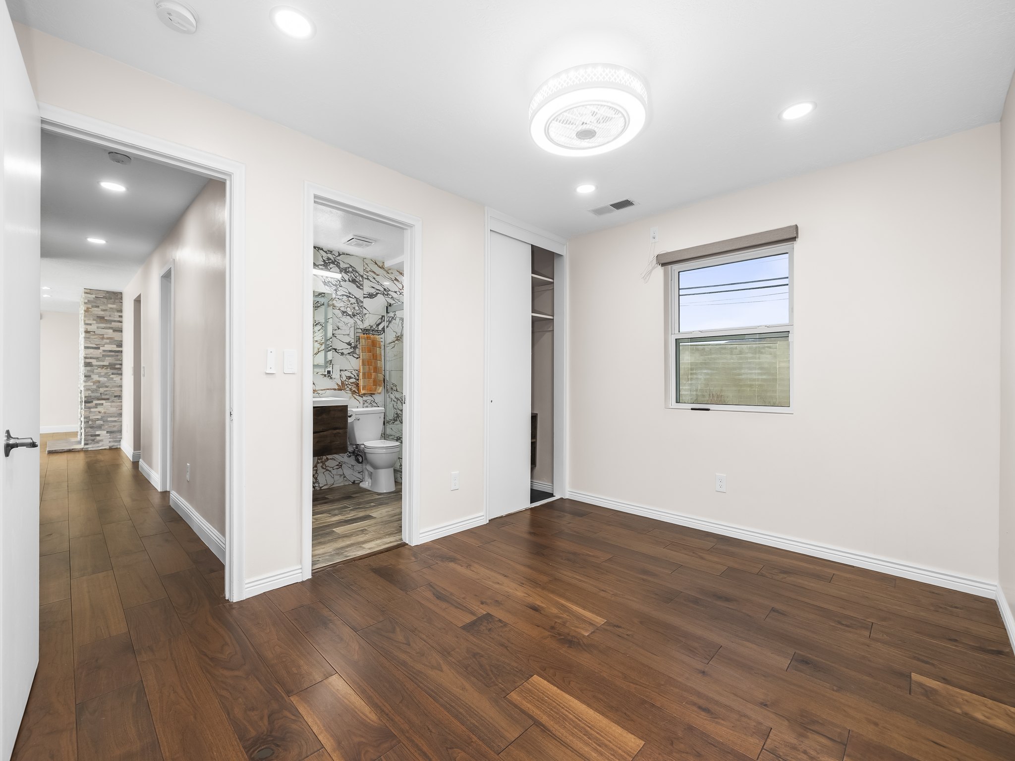Unfurnished bedroom featuring dark wood-type flooring, a closet, connected bathroom, and recessed lighting