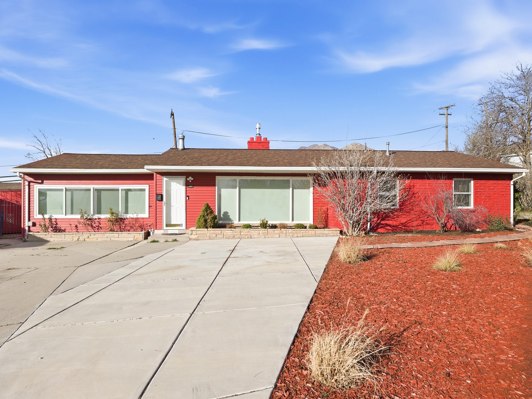 Ranch-style home with brick siding, a shingled roof, and a chimney