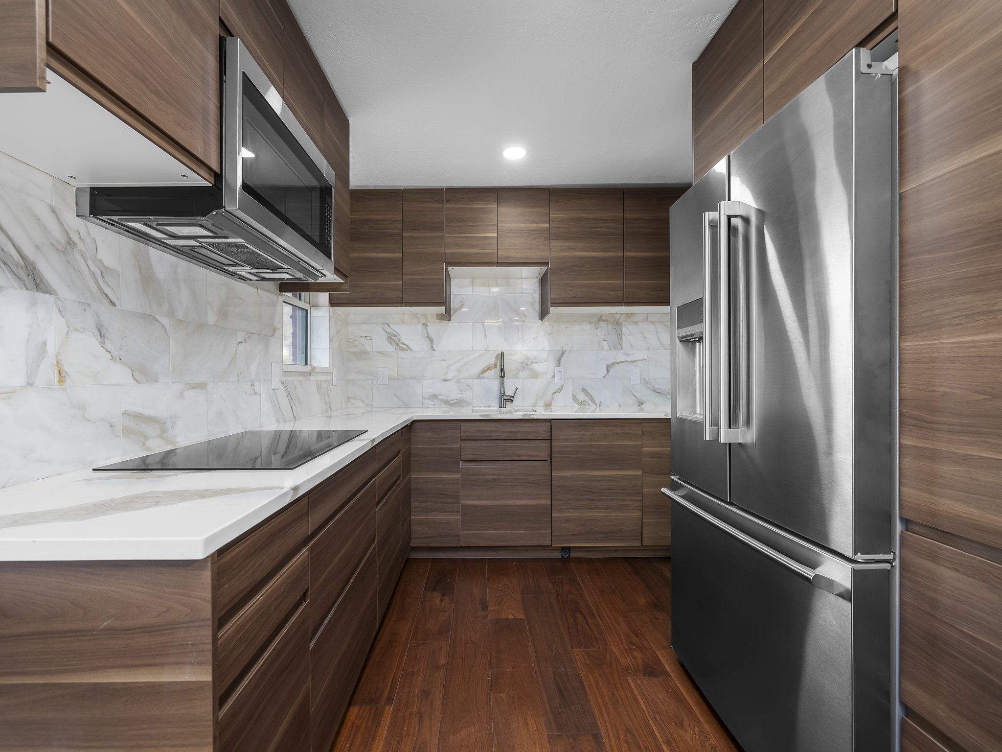 Kitchen featuring modern cabinets, stainless steel appliances, light stone countertops, dark wood finished floors, and wood finish cabinetry