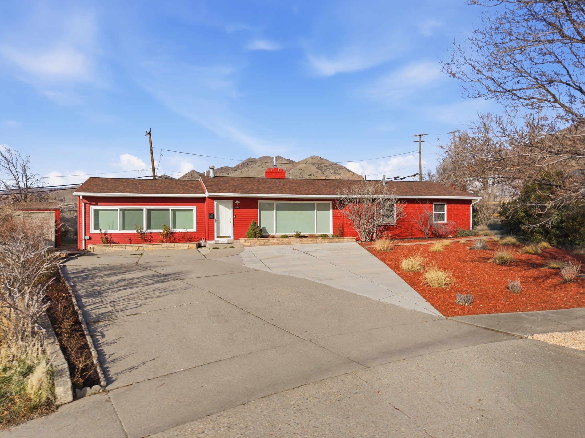 Ranch-style house featuring brick siding, roof with shingles, and concrete driveway