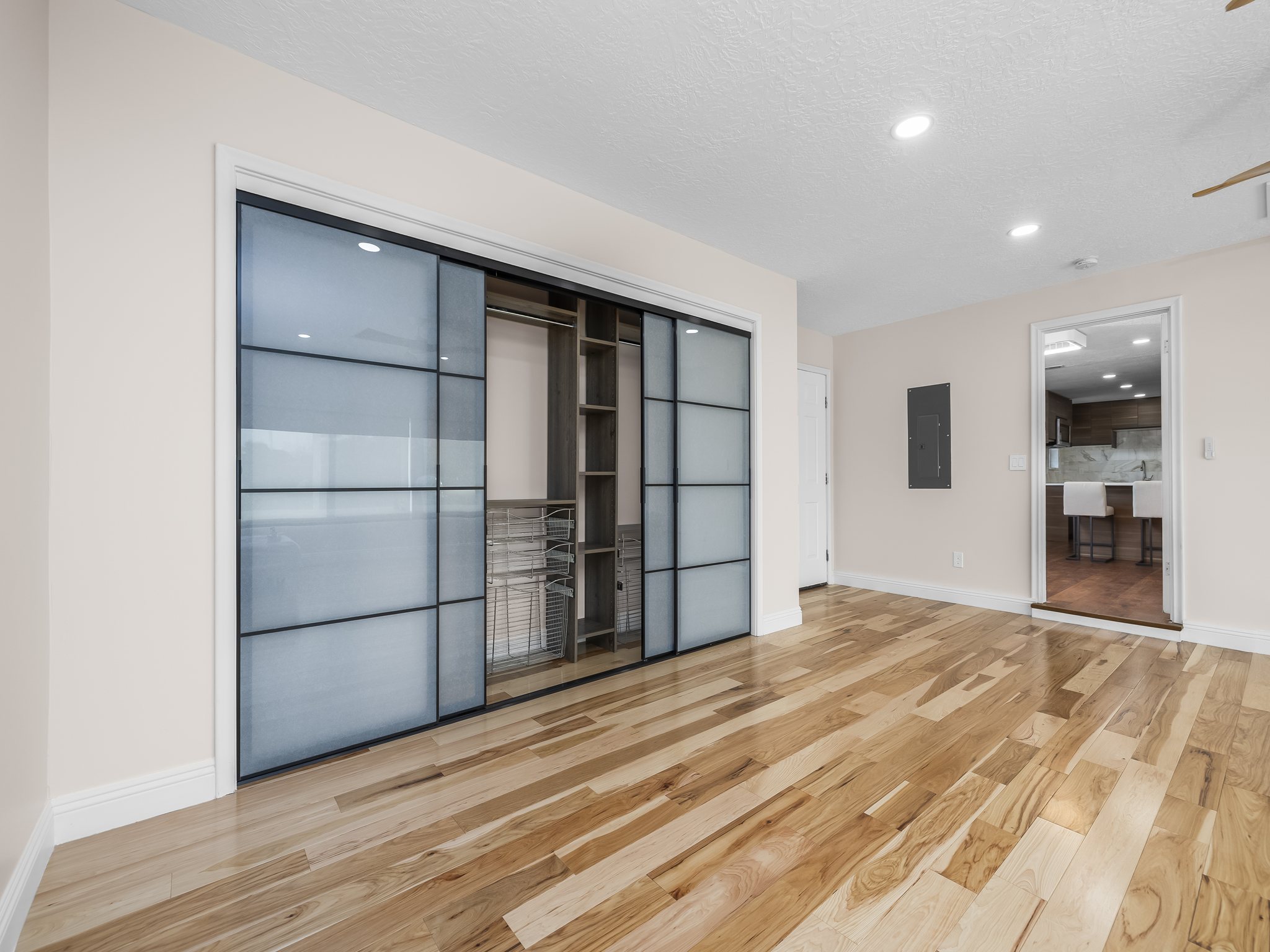 Unfurnished bedroom with a closet, recessed lighting, light wood-type flooring, electric panel, and a textured ceiling