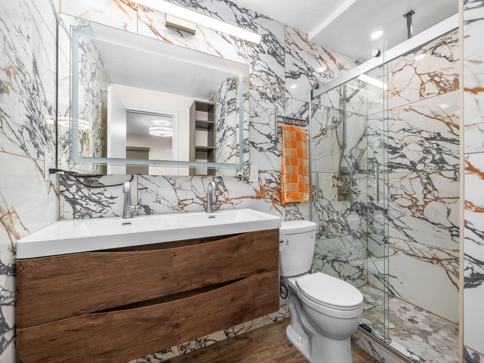 Full bath with a marble finish shower, tile walls, double vanity, and stone wall