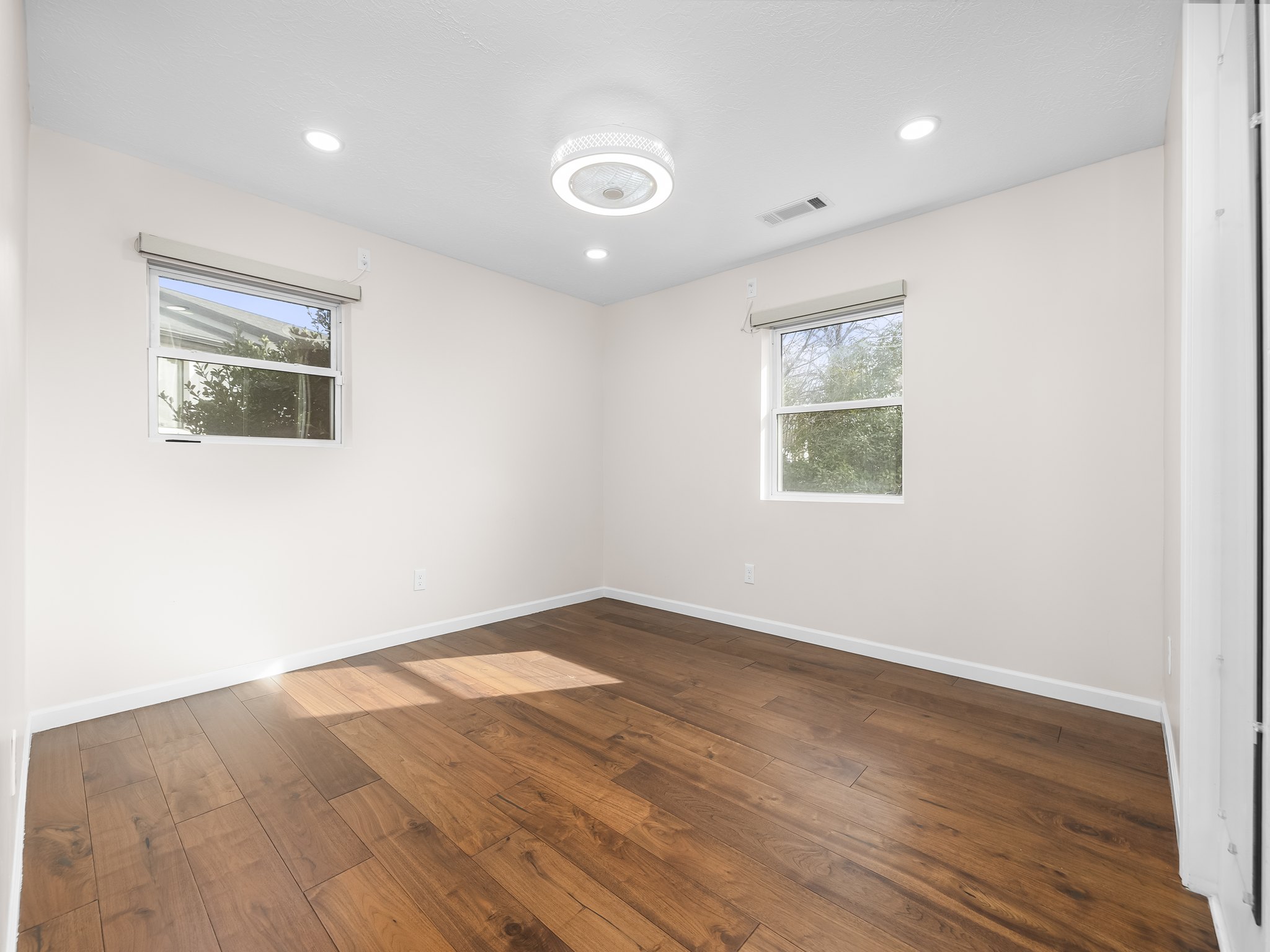 Empty room with dark wood finished floors, recessed lighting, and healthy amount of natural light