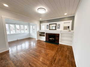 Unfurnished living room featuring dark wood-type flooring, recessed lighting, wood ceiling, crown molding, and a brick fireplace