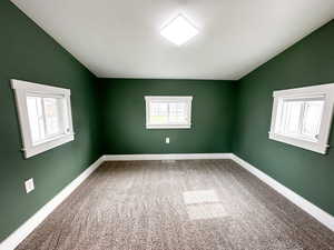 Unfurnished room with vaulted ceiling and light carpet