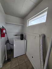 Laundry area featuring washer / dryer and dark tile patterned flooring