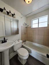Bathroom with bathtub / shower combination, a textured ceiling, and dark wood-style floors