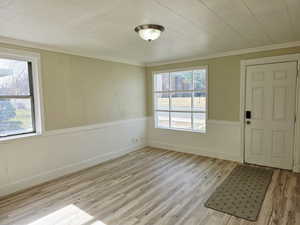 Foyer featuring light wood-style flooring, wainscoting, and ornamental molding