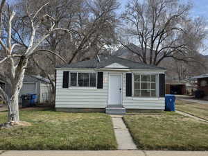 View of front facade with a front lawn and a shingled roof