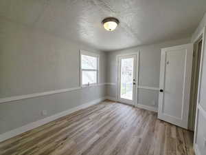 Empty room featuring a textured wall, a textured ceiling, and light wood-style floors