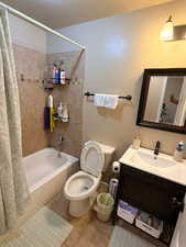 Bathroom with vanity, shower / bath combination with curtain, and light tile patterned flooring