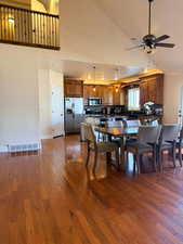 Dining space with ceiling fan, dark wood finished floors, and lofted ceiling