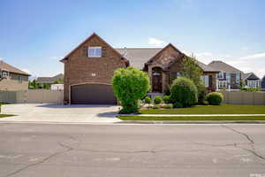 View of front facade with a gate, brick siding, driveway, an attached garage, and a residential view