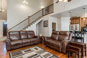 Living room with a high ceiling, ceiling fan, light wood-type flooring, and hanging lights