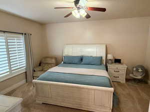 Bedroom with a ceiling fan and dark carpet