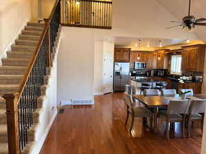 Dining space featuring a ceiling fan, dark wood-style flooring, and vaulted ceiling