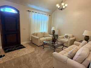 Carpeted living room with hanging lights, lofted ceiling, and tile patterned floors