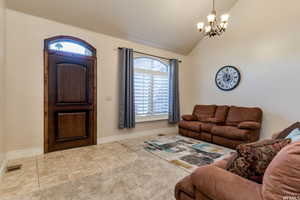 Living area featuring vaulted ceiling, tile patterned flooring, a chandelier, and healthy amount of natural light