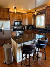 Kitchen featuring stainless steel appliances, a breakfast bar area, a textured ceiling, a center island, and hanging light fixtures