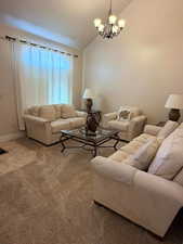 Living room with carpet flooring, a chandelier, and lofted ceiling
