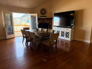 Dining room featuring dark wood-style flooring, lofted ceiling, healthy amount of natural light, and a stone fireplace