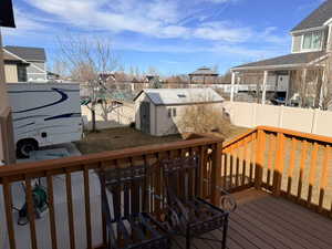 Deck with a residential view, a storage shed, and a fenced backyard