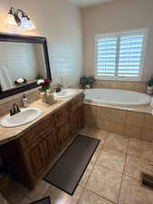 Full bathroom featuring double vanity, a garden tub, and light tile patterned floors