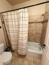 Full bathroom featuring shower / bathtub combination with curtain and light tile patterned floors
