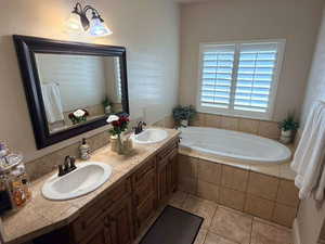 Full bath featuring double vanity, light tile patterned floors, and a garden tub