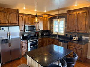 Kitchen with stainless steel appliances, dark stone counters, dark wood finished floors, wood finish cabinets, and a textured ceiling