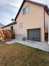 Rear view of house with a yard, stucco siding, a patio area, a wooden deck, and a garage