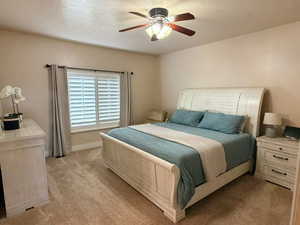 Bedroom with a ceiling fan, light colored carpet, and a textured ceiling