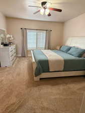 Bedroom featuring a ceiling fan, light carpet, and a textured ceiling