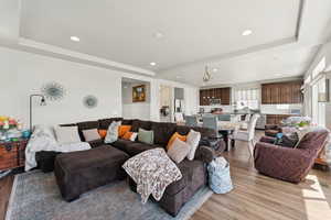 Living room featuring a tray ceiling, light wood finished floors, and recessed lighting