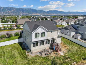 Back of house featuring a mountain view, board and batten siding, roof with shingles, and a fenced backyard