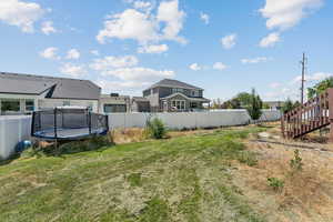 Fenced backyard featuring a trampoline