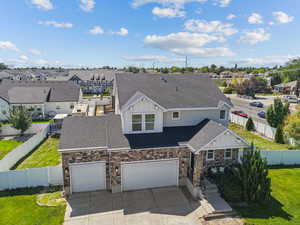 View of front of property featuring roof with shingles, concrete driveway, a residential view, board and batten siding, and stone siding