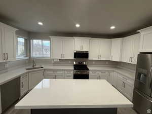Kitchen featuring stainless steel appliances, white cabinets, recessed lighting, light stone counters, and a kitchen island