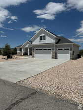 Craftsman-style house with stone siding, driveway, board and batten siding, and a garage