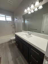 Full bath featuring vanity, dark wood-style floors, and bathing tub / shower combination