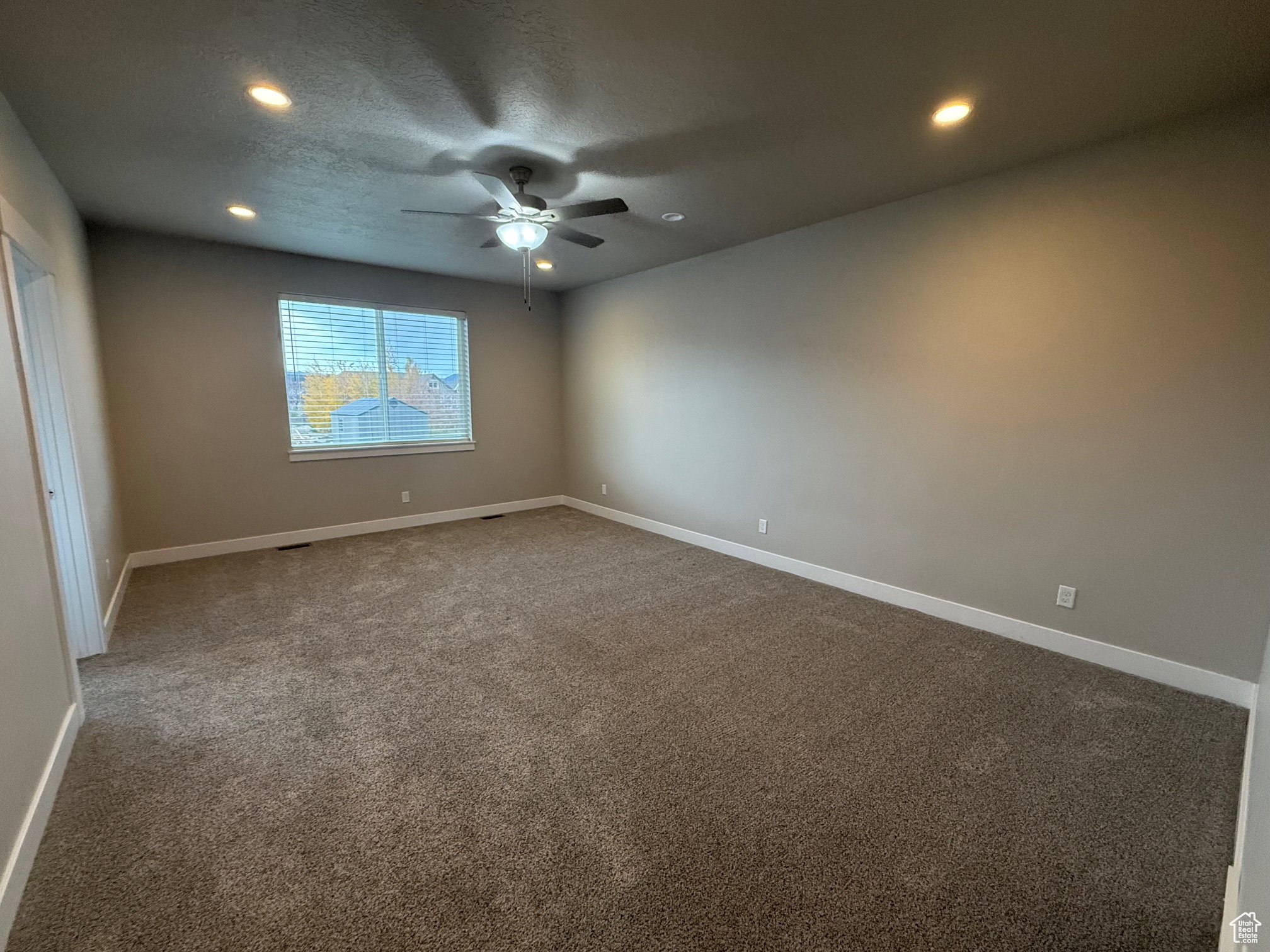 Carpeted empty room with recessed lighting, ceiling fan, and a textured ceiling