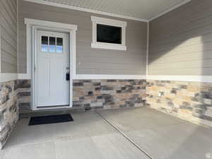 Property entrance featuring stone siding and a patio