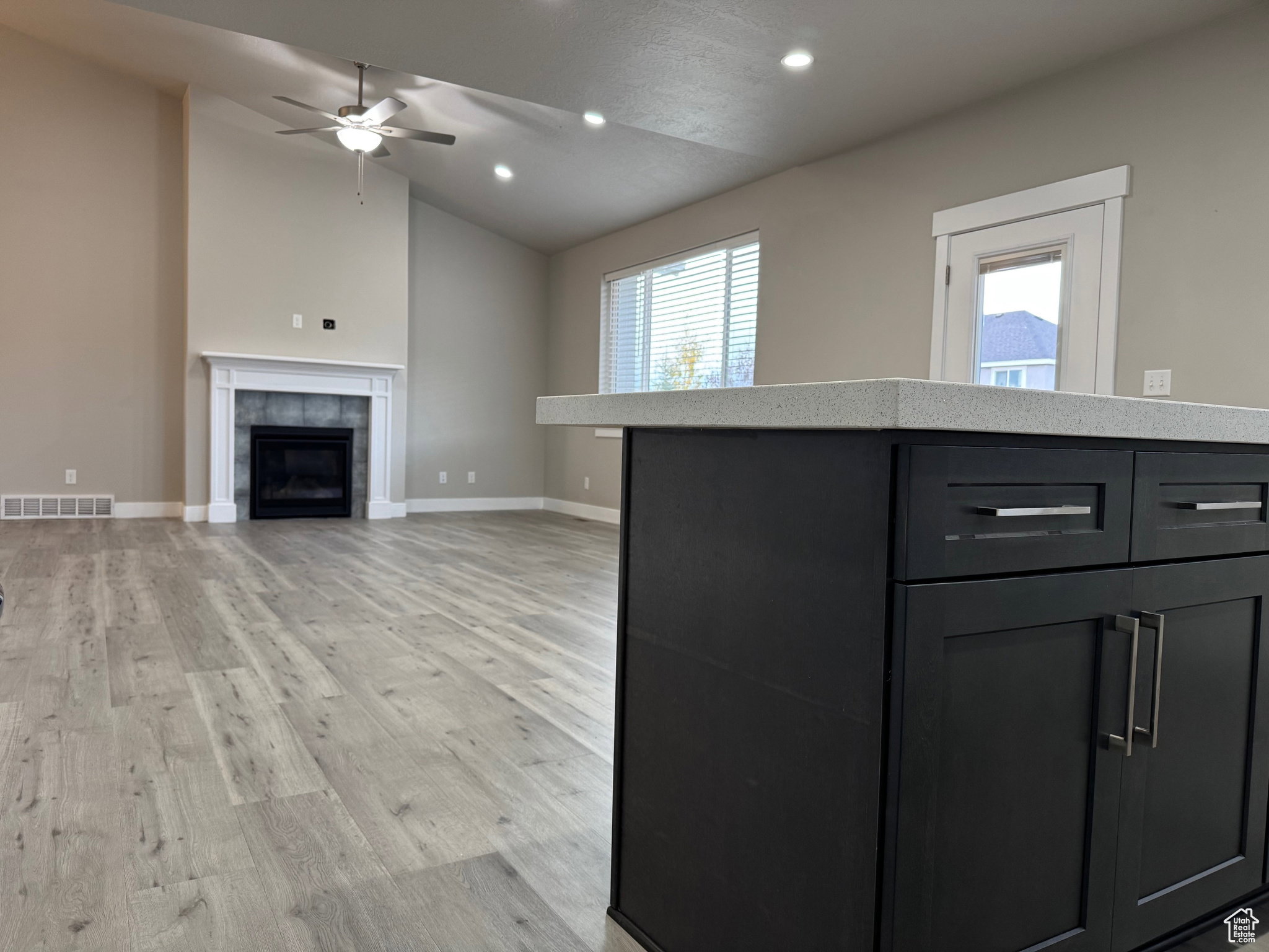 Kitchen featuring a center island, lofted ceiling, light wood-type flooring, dark cabinets, and recessed lighting