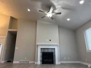 Unfurnished living room with lofted ceiling, light wood-style flooring, a tile fireplace, recessed lighting, and a ceiling fan