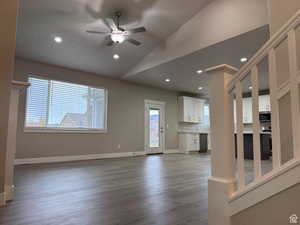 Unfurnished living room featuring a ceiling fan, dark wood-style floors, lofted ceiling, and recessed lighting