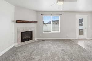 Unfurnished living room with a premium fireplace, carpet, and ceiling fan