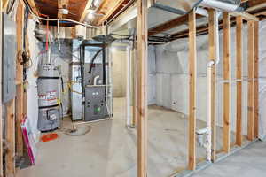 Unfinished basement with heating unit, water heater, and electric panel