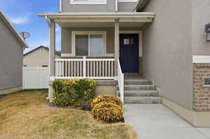 View of exterior entry with covered porch and stucco siding
